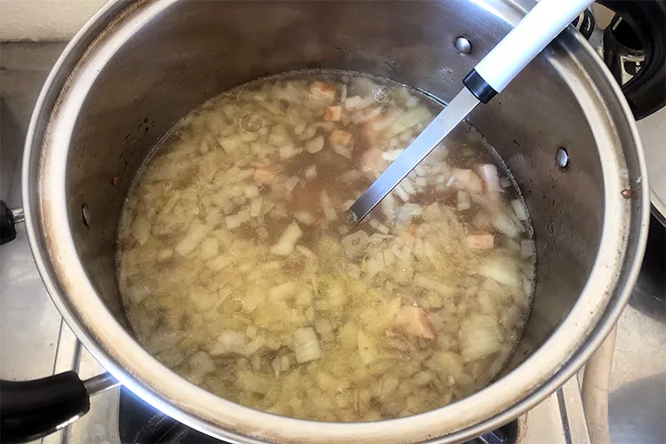 玉ねぎとベーコンが入った鍋に水を入れた様子