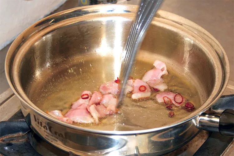 ベーコンと赤唐辛子を炒める様子