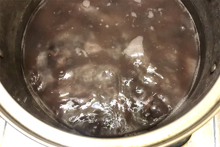 鍋で煮ていた紫花豆に砂糖を加えてさらに煮る様子