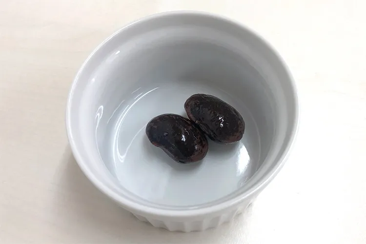 器の中に入れられた紫花豆の煮豆2粒