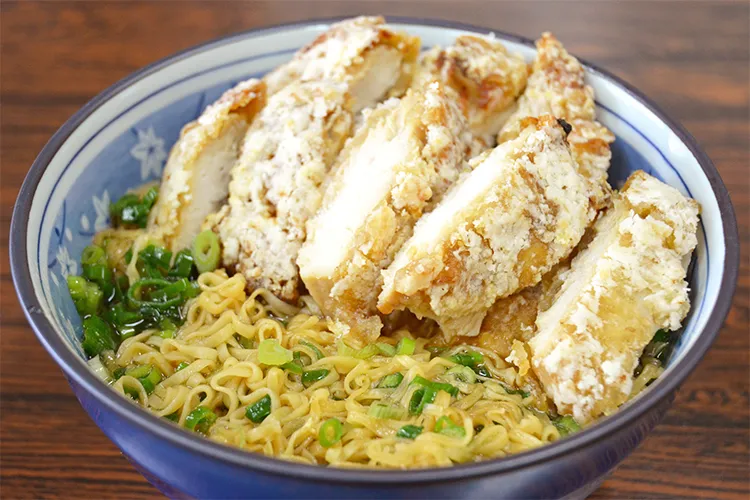ネギ入りチキンラーメンの上に切り分けられた山賊焼が大量に乗っている様子