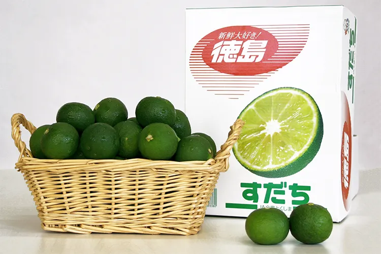徳島県産すだちのパッケージとカゴに盛られたすだち